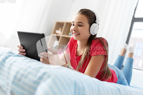 Image of girl in headphones listening to music on tablet pc