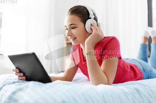 Image of girl in headphones listening to music on tablet pc