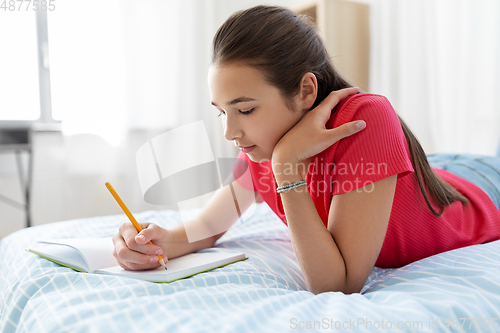 Image of teenage girl writing to diary at home