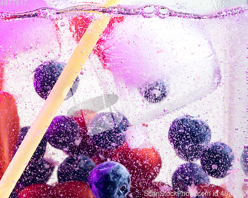 Image of Close up view of the cold and fresh lemonade with bright berries in neon light