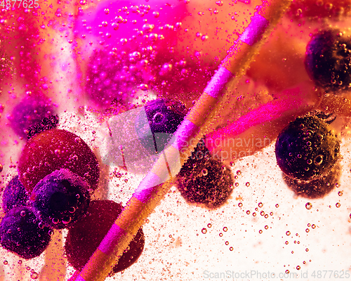 Image of Close up view of the cold and fresh lemonade with bright berries in neon light