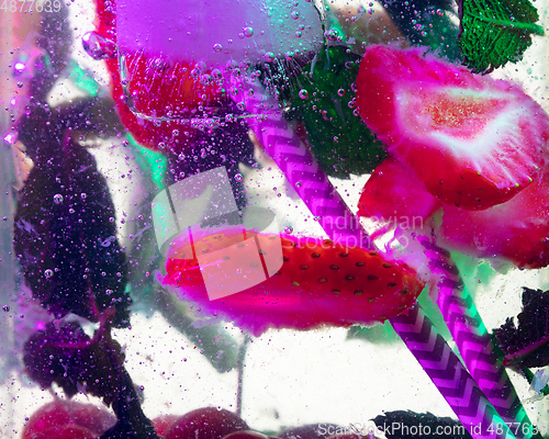 Image of Close up view of the cold and fresh lemonade with bright berries in neon light