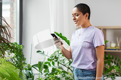 Image of african american woman with smartphone at home