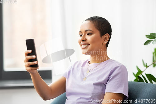 Image of african american woman with smartphone at home
