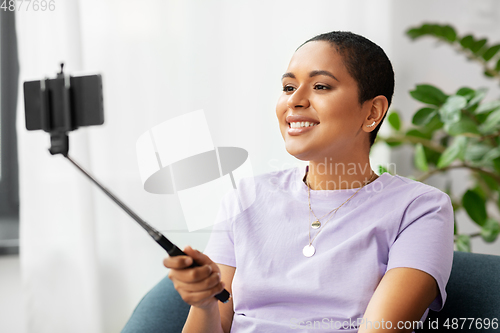 Image of happy african american woman taking selfie at home