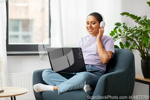 Image of woman with laptop listening to music at home