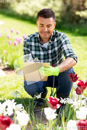 Image of man with clipboard and flowers at summer garden