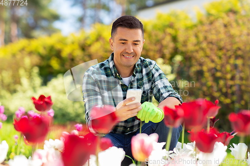 Image of middle-aged man with smartphone at flower garden