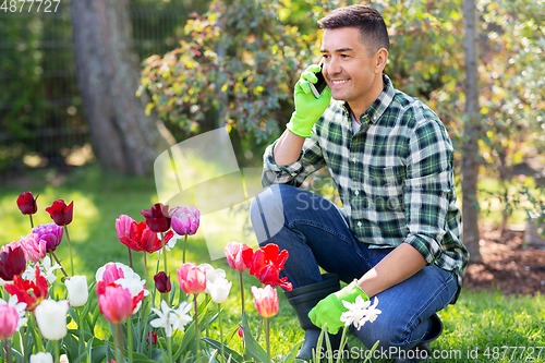 Image of man with flowers calling on smartphone at garden