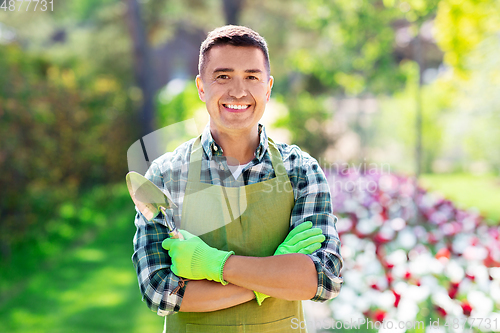 Image of happy man in apron with scoop at summer garden