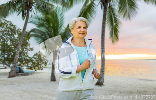 Image of senior woman running along summer park