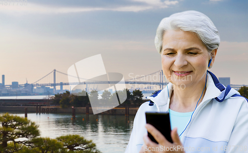 Image of sporty senior woman with earphones and smartphone