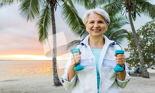 Image of senior woman with dumbbells exercising at park