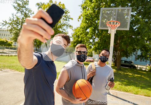 Image of happy men taking selfie on basketball playground