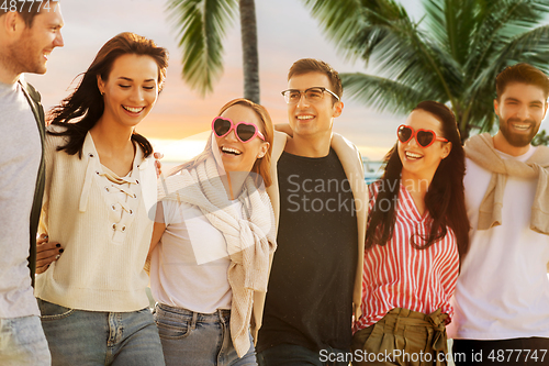 Image of happy friends walking along summer beach