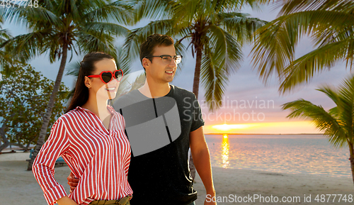 Image of happy couple walking along summer beach