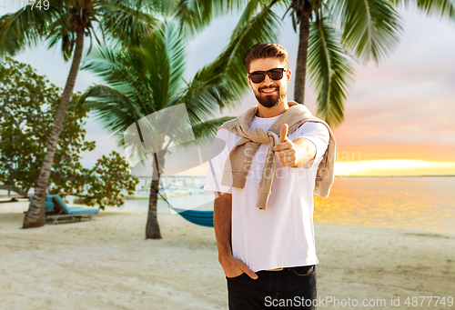 Image of happy man on beach showing thumbs up