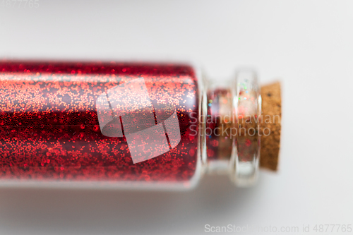 Image of red glitters in bottle over white background