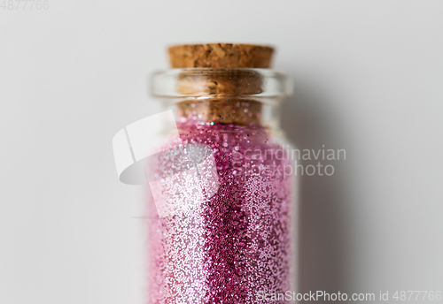 Image of pink glitters in bottle over white background