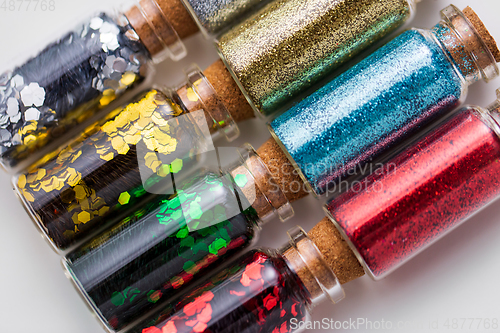 Image of set of different glitters in small glass bottles