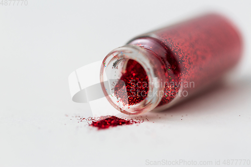 Image of red glitters poured from small glass bottle