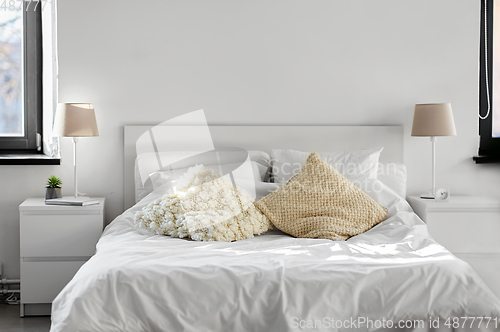 Image of cozy bedroom with cushions and bed linen at home