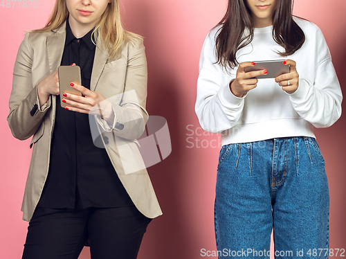 Image of Two girls, friends using mobile smartphones. Teenagers addiction to new technology trends. Close up.