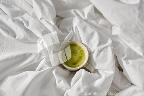 Image of cup of matcha tea in bed at home