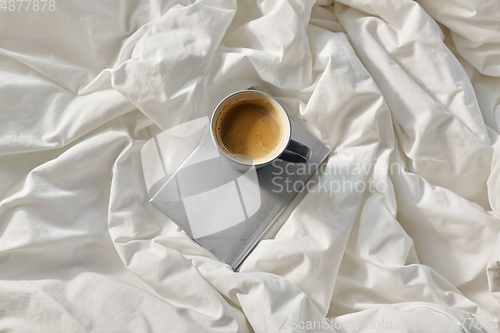 Image of cup of coffee with book in bed