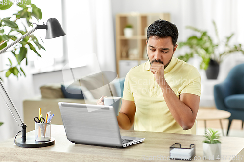 Image of ill indian man with laptop coughing at home office