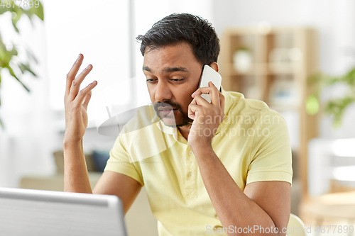 Image of man calling on smartphone at home office