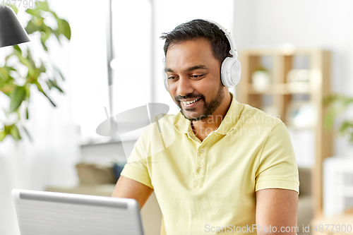 Image of man in headphones with laptop working at home