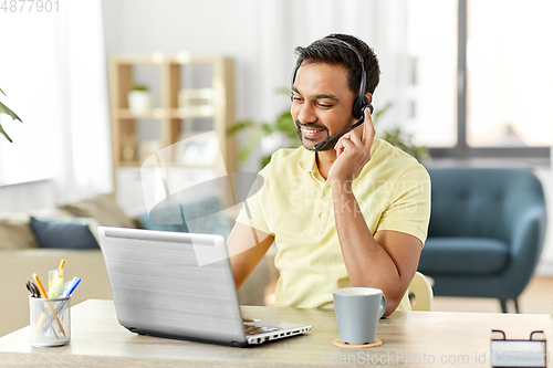 Image of indian man with headset and laptop working at home