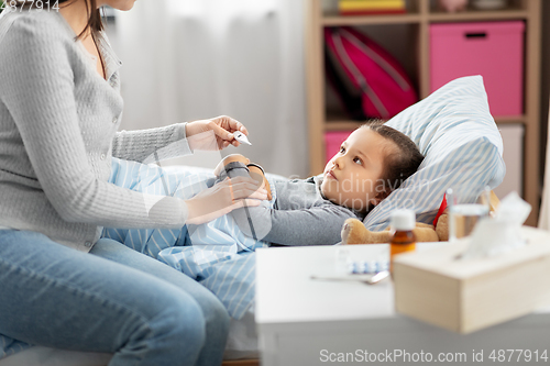 Image of mother measuring temperature of sick daughter