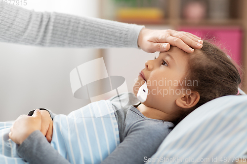 Image of mother and sick daughter measuring temperature