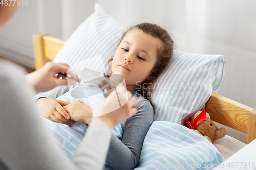 Image of mother pouring cough syrup for sick daughter