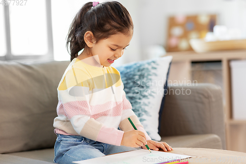 Image of little girl drawing with coloring pencils at home