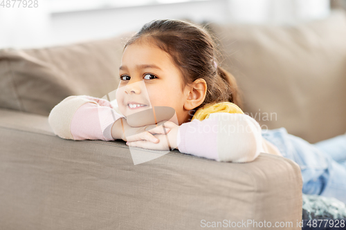 Image of happy smiling little girl lying on sofa at home