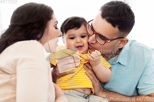 Image of happy mother and father kissing baby son at home