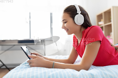 Image of girl in headphones listening to music on tablet pc