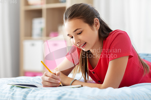 Image of teenage girl writing to diary at home