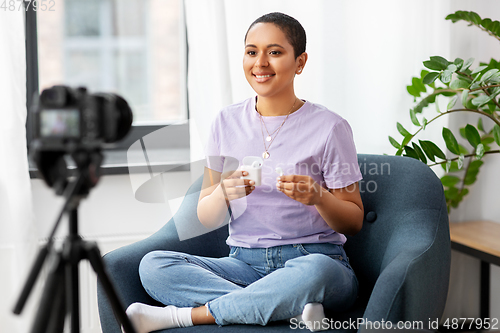 Image of female blogger with camera video blogging at home