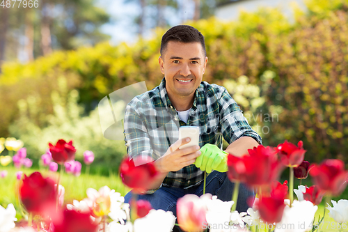 Image of middle-aged man with smartphone at flower garden