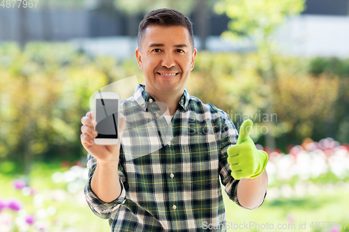 Image of man with smartphone showing thumbs up at garden