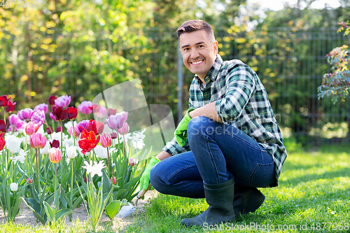 Image of man with scoop taking care of flowers at garden