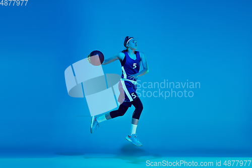 Image of Young caucasian female basketball player isolated on blue studio background in neon light