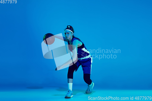 Image of Young caucasian female basketball player isolated on blue studio background in neon light