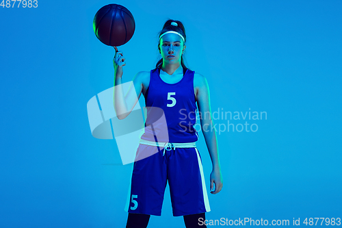 Image of Young caucasian female basketball player isolated on blue studio background in neon light