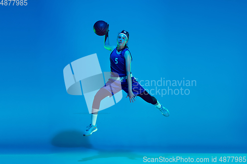 Image of Young caucasian female basketball player isolated on blue studio background in neon light