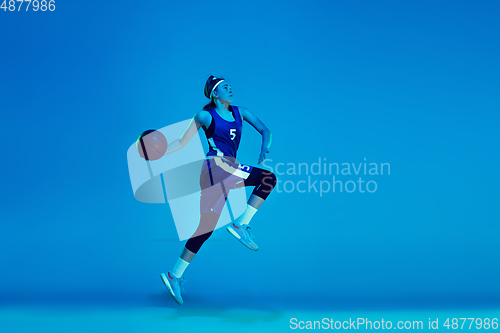 Image of Young caucasian female basketball player isolated on blue studio background in neon light